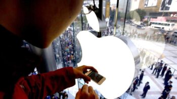 Một người đàn ông dùng iPhone của mình chụp ảnh những người dân đang bước vào một cửa hàng Apple.