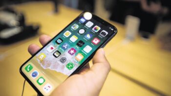 Một khách hàng cầm điện thoại thông minh iPhone X của Apple Inc. trong buổi ra mắt bán hàng tại một cửa hàng ở New York, Hoa Kỳ, vào thứ Sáu, ngày 3 tháng 11 năm 2017. Mức giá 1.000 USD trên iPhone X mới của Apple Inc. những người đam mê trên khắp thế giới đã chờ đợi -- đôi khi qua đêm -- thành hàng dài mà không có gì đảm bảo rằng họ sẽ bước ra khỏi cửa hàng với một trong những thiết bị được thèm muốn.
