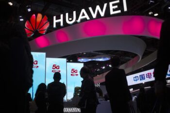 Những người tham dự đi ngang qua màn hình hiển thị các dịch vụ 5G của công ty công nghệ Trung Quốc Huawei.