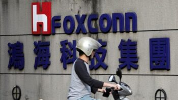 Một người đi xe máy ngang qua logo của Foxconn, tên giao dịch của Hon Hai Precision Industry, tại Đài Bắc, Đài Loan ngày 30 tháng 3 năm 2018.